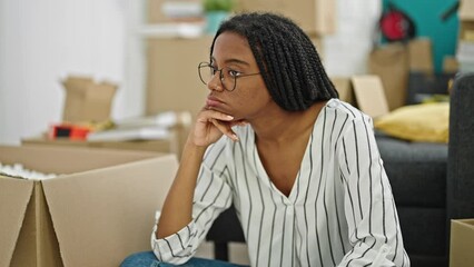 Wall Mural - African american woman sitting on floor with serious expression at new home