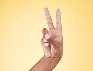 Closeup, hands and peace sign with emoji, support and voice on a yellow studio background. Hand of female, person and model showing v symbol, icon or shape for hope, trust in vote and mockup space