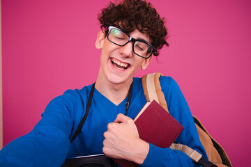 Wall Mural - Attractive guy posing on a pink background. The student is happy and sad.