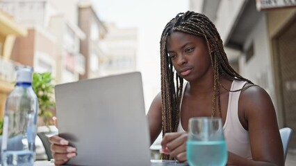 Canvas Print - African american woman using laptop sitting on table smiling at coffee shop terrace