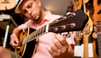 Wall Mural - Young musician tuning a classical guitar in a guitar shop