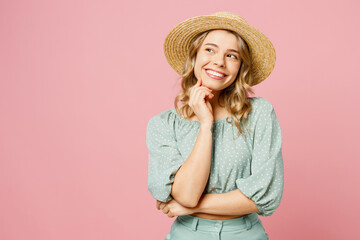 Wall Mural - Young smiling happy woman she wear summer casual clothes straw hat put hand prop up on chin, lost in thought and conjectures isolated on plain pastel light pink background studio. Lifestyle concept.