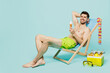 Full body smiling happy fun young sexy man wear green shorts swimsuit relax near hotel pool sit in deckchair eat icecream isolated on plain blue background. Summer vacation sea rest sun tan concept.