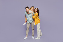 Full Body Young Joyful Happy Parents Mom Dad With Child Kid Daughter Girl 6 Years Old Wear Blue Yellow Casual Clothes Giving Piggyback Ride To Joyful, Sit On Back Isolated On Plain Purple Background.