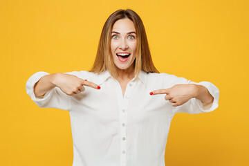 Young surprised shocked caucasian happy woman she wears white shirt casual clothes point index fingers on herself looking camera isolated on plain yellow background studio portrait. Lifestyle concept.