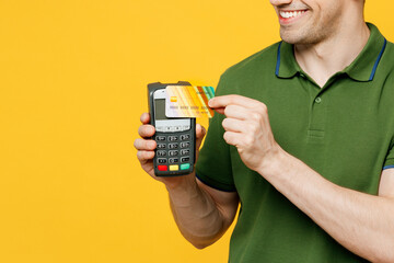 Poster - Cropped young man he wears green t-shirt casual clothes hold wireless modern bank payment terminal to process acquire credit card isolated on plain yellow background studio portrait Lifestyle concept