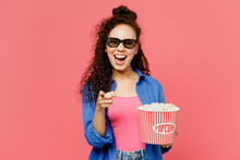 Young Cheerful Excited Woman Of African American Ethnicity In 3d Glasses Watch Movie Film Hold Bucket Of Popcorn In Cinema Point Finger Camera On You Isolated On Plain Pastel Pink Background Studio.