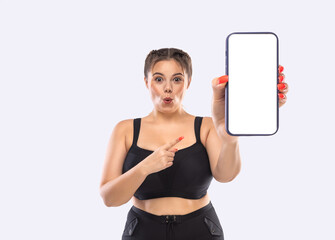 Size plus model advertises black friday sale in online shop with big sizes. Dietetic fitness program template. Girl demonstrates the screen of a smartphone for the presentation of a mobile application