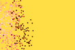 Metallic red confetti in a heart shape scattered on a yellow background. Composition with place for text.