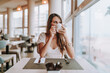 Chica joven tomando cafe en cafeteria de hotel
