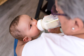 Unrecognizable adult giving a bottle to an infant