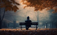Person Sitting Alone In A Bench In A Park In Autumn Time