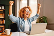 Joyful business woman freelancer entrepreneur smiling and hands in the air celebrating success at work.