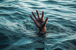 © VisualProduction - A desperate hand in the water looking for help. Person under water waving for help.