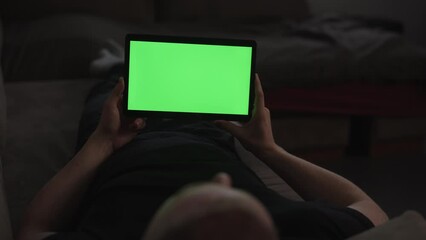 Sticker - Man at home lying on a couch with tablet pc with green screen