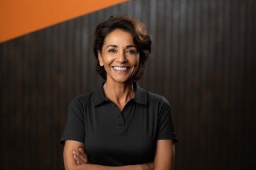 Medium shot portrait of an Indian woman in her 50s against an abstract background wearing a sporty polo shirt