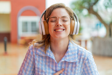 Poster - Young redhead girl headphones at outdoors smiling a lot