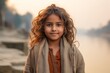 © Leon Waltz - Portrait of a little girl with curly hair in a warm sweater on the background of the river.