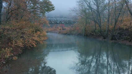Wall Mural - Scenic vintage steel bridge over autumn forest and blue river with fog in mountain misty country rustic location 