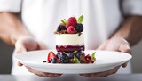 Closeup of male hands holding white plate with fresh berry dessert