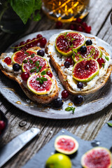 Toast spread with cream cheese, figs, currants and honey. Tasty and healthy brunch. Colourful scene.