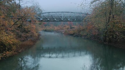 Wall Mural - Old rustic steel bridge over autumn green river with fog in mountain country scenic location 