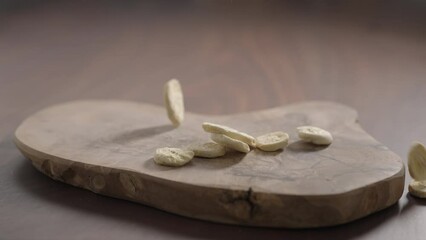 Wall Mural - Slow motion freeze dried banana chips fall on olive board