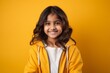 © Eber Braun - Cheerful little girl in yellow hoodie looking at camera over yellow background