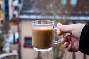 Canvas Print - a cup of coffee is held above a glass container outside