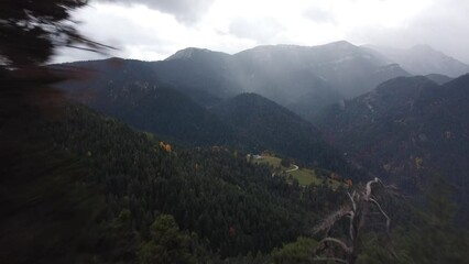 Wall Mural - Drone footage flying over landscape green forest range mountains with misty cloudy sky