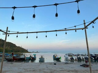 Canvas Print - Scenic beach shoreline with a row of docked boats and a light pole