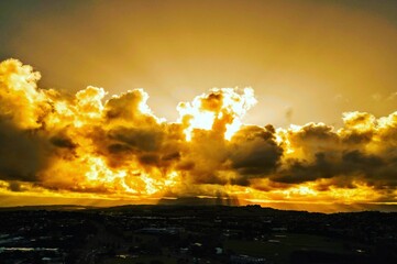 Poster - Vibrant golden sky is depicted with clouds and a rolling hill in the foreground