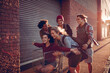 © Marko Geber - Diverse group of young people walking on a sidewalk and having fun pushing a shopping cart in the city
