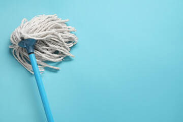 Poster - Mop with plastic handle on light blue background, top view. Space for text