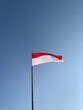 indonesian flag fluttering with blue clouds background