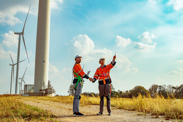 Team engineers technical two aimed men discussing wind turbines on sunny day brainstorming fieldwork successful handshake wind turbine maintenance natural resources renewable energy.