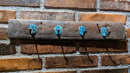 Old wooden clothes hanger with metal hooks on brick wall