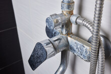 A Thin Stream Of Hard Water Flows From An Old Tap Aerator. Old Bathroom Sink Faucet Contaminated With Calcium And Grime.