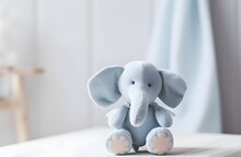 A Cute Light Gray Toy Elephant Is Sitting On A Wooden Table, With A Blurred, Bright, And Cozy Nursery Room In The Background. For Baby Shower, Card Design With Copy Space. 