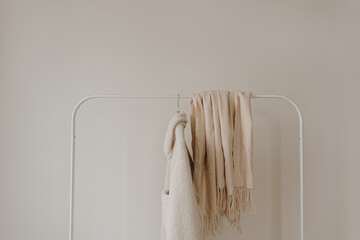 Wall Mural - White warm woolen autumn seasonal jacket and skirt on hanger over white wall. Minimalist fashion clothes wardrobe