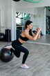 © RomanR - Young attractive slim woman wear sport cloth doing exercise with fitball at fitness center
