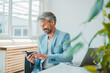 © Westend61 - Smiling businessman using mobile phone sitting at desk in office