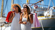 © NDABCREATIVITY - Fashionable women out on the street with shopping bags enjoying summer vacation and travel.