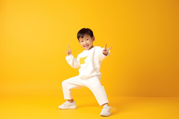 Pretty asian preschool boy in sports clothing doing some fun dance moves