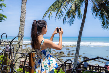 Sticker - Tourist woman use mobile phone to take photo at seaside cafe