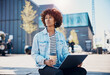 © Flamingo Images - Young woman having coffee and working on a laptop on a city bench