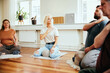 © Flamingo Images - Yoga instructor leading students in a meditation