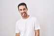 © Krakenimages.com - Handsome hispanic man standing over white background sticking tongue out happy with funny expression. emotion concept.
