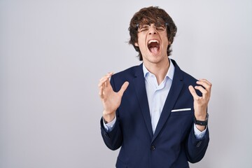 Canvas Print - Hispanic business young man wearing glasses crazy and mad shouting and yelling with aggressive expression and arms raised. frustration concept.