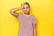 © Asier - Shaved head woman in red striped tee, yellow backdrop tired and very sleepy keeping hand on head.